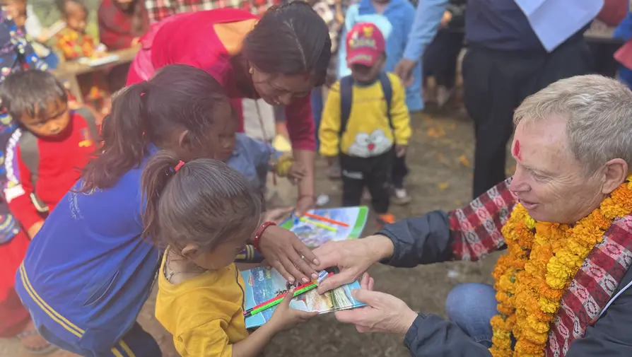 Handing out pencils and writing books to the students.